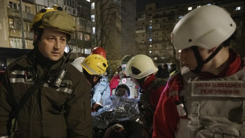 Des sauveteurs et des auxiliaires médicaux évacuent une femme âgée près d'un immeuble résidentiel endommagé à la suite d'une attaque de drone à Kiev, le 23 mars 2025, dans le cadre de l'invasion russe de l'Ukraine. (GENYA SAVILOV/AFP via Getty Images) 