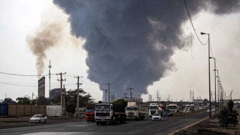 Une épaisse fumée s'élève alors que des automobilistes circulent sur une autoroute près du lieu d'une explosion au port de Shahid Rajaee, en Iran, le 26 avril 2025. (MOHAMMAD RASOLE MORADI/IRNA/AFP via Getty Images)